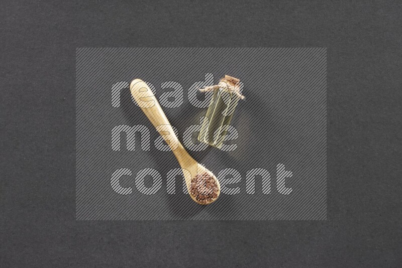 وعاء خشبي ممتلئ بحبوب بذر الكتان مع زجاجة من زيت بذر الكتان علي خلفية سوداء