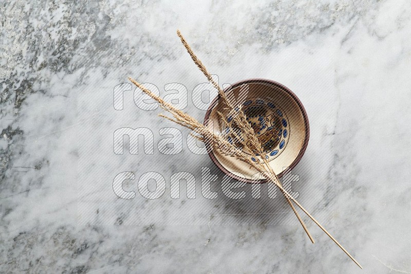 Wheat stalks on Decorative Pottery Plate on grey marble flooring, Top view