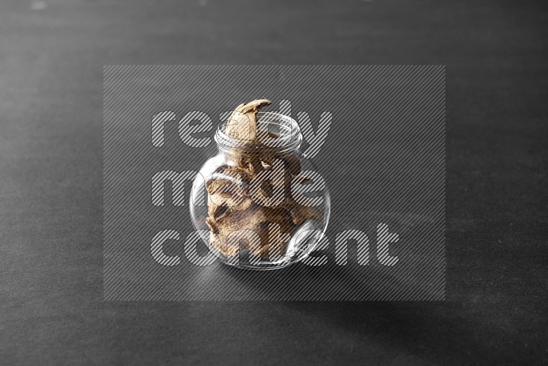 A glass spice jar full of ginger on black flooring