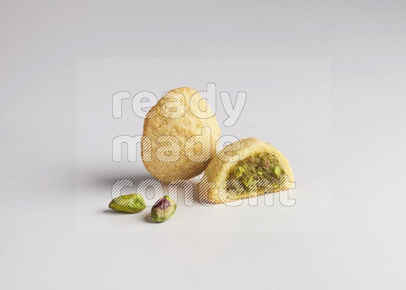 Two Pieces of Maamoul filled with pistachio paste  one of them is cut direct on white background