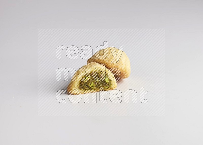 Two Pieces of Maamoul filled with pistachio paste  one of them is cut direct on white background