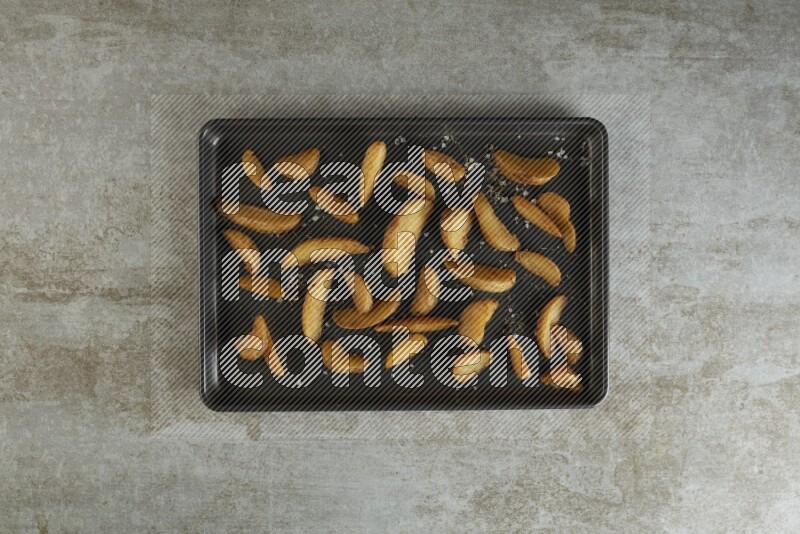 wedges potato in a black stainless steel rectangle tray on grey textured counter top