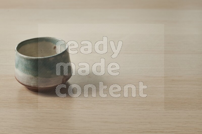 وعاء فخاري متعدد الألوان على خلفية خشبية فاتحة