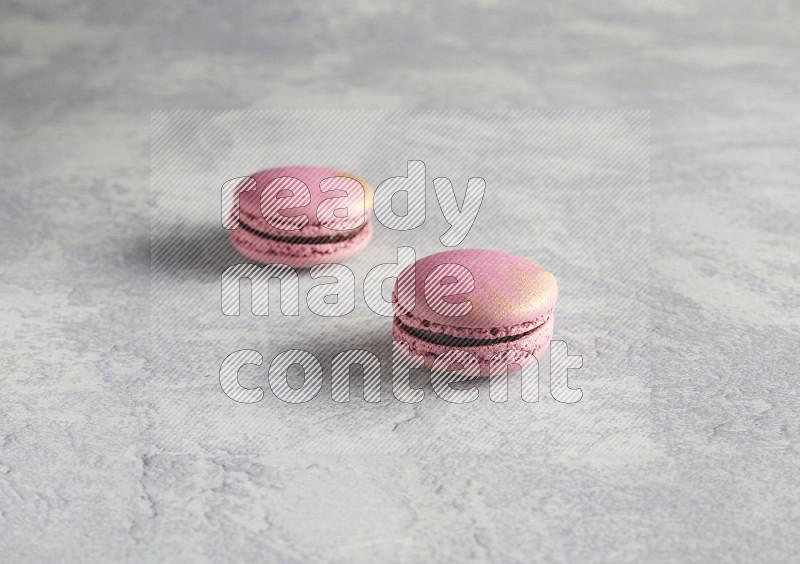 45º Shot of two Purple Strawberry macarons on white  marble background