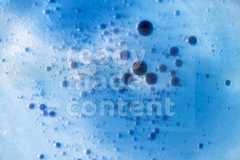 Close-ups of abstract blue watercolor drops on oil Surface on blue background