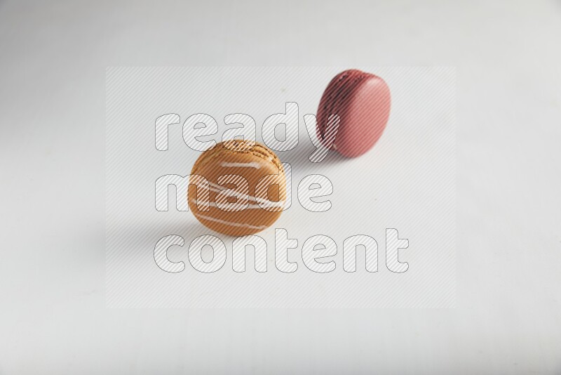45º Shot of of two assorted Brown Irish Cream, and Red Velvet macarons on white background