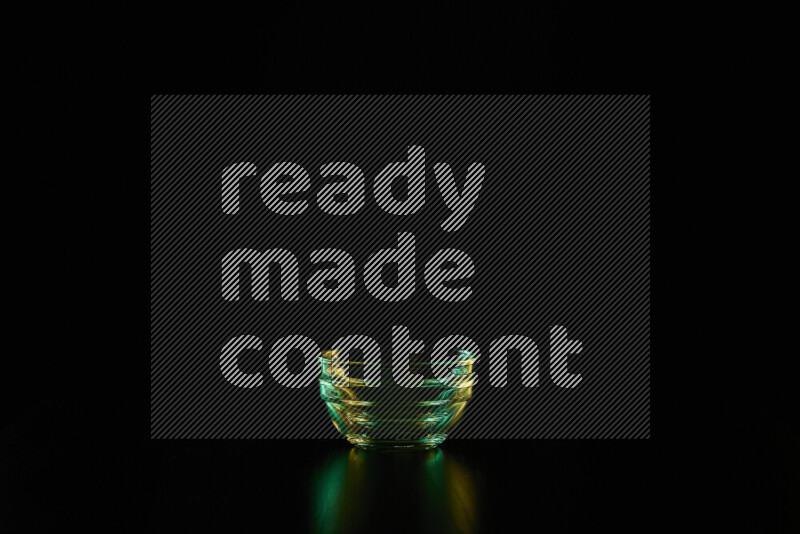 Glassware with rim light in green and yellow against black background