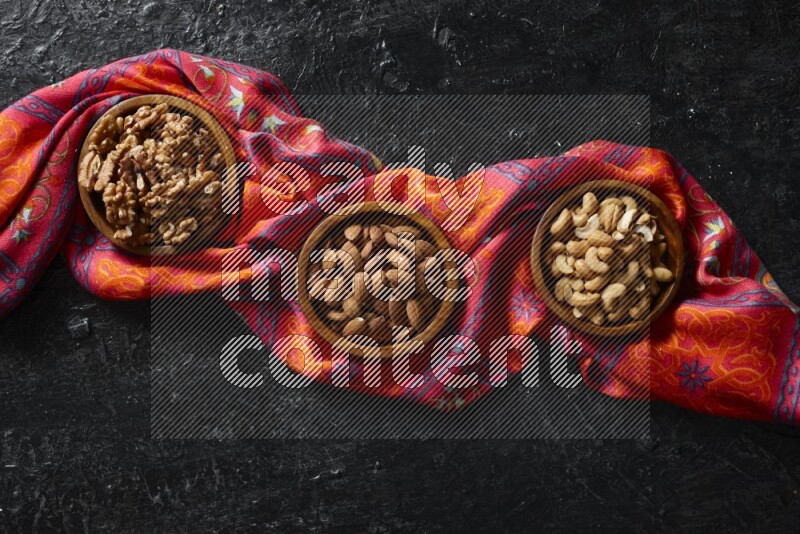 مكسرات في أطباق خشبية علي خلفية سوداء