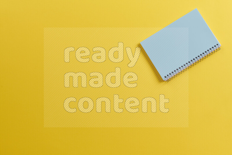 A blue notebook with different school supplies on yellow background