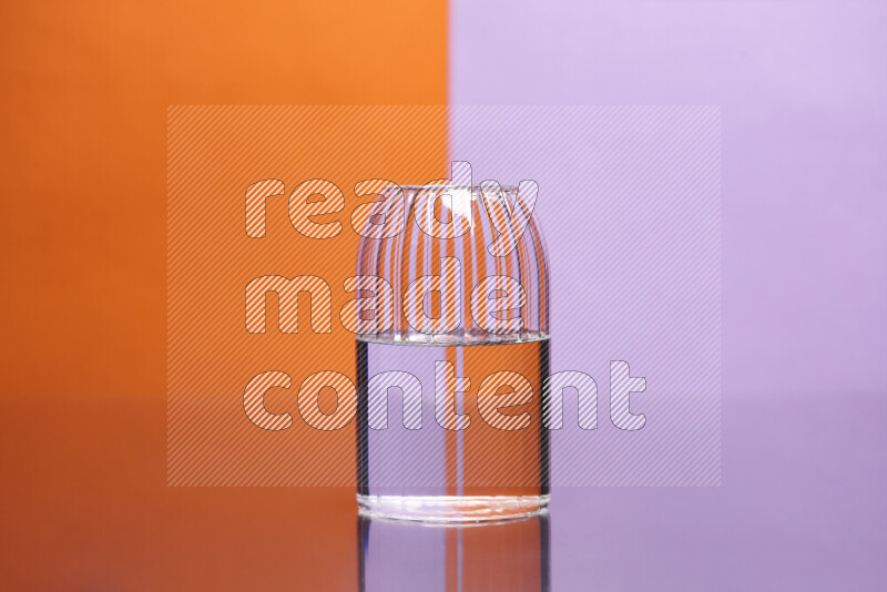 The image features a clear glassware filled with water, set against orange and light purple background