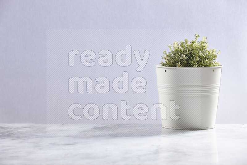 Artificial plant in white pot on grey marble background