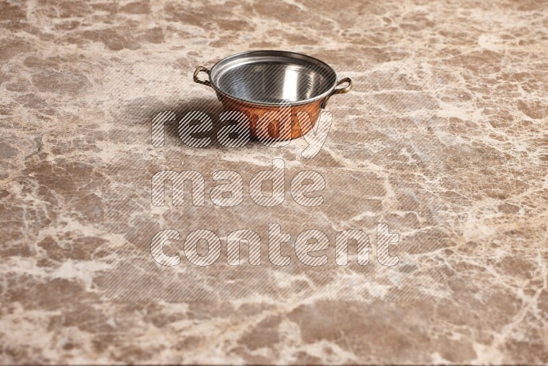A small copper pot on beige marble background