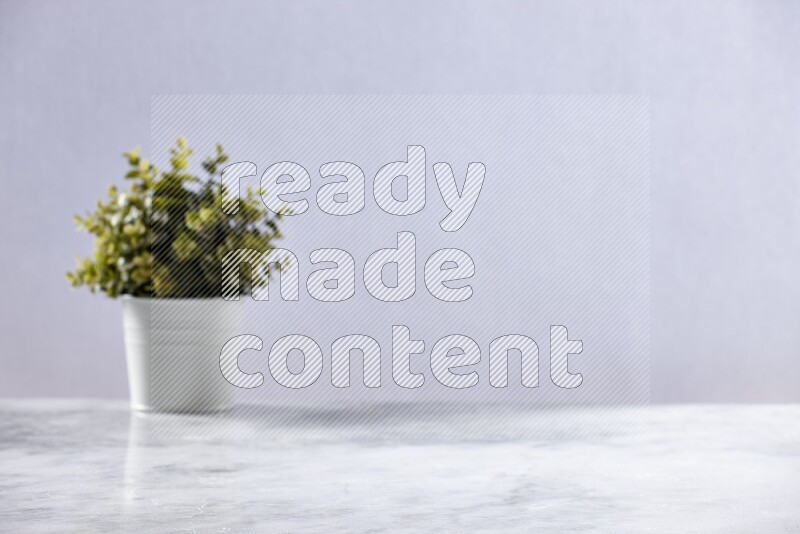 Artificial plant in white pot on grey marble background