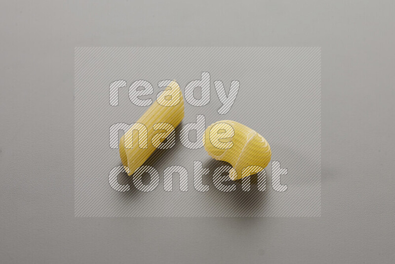 Penne pasta with other types of pasta on grey background