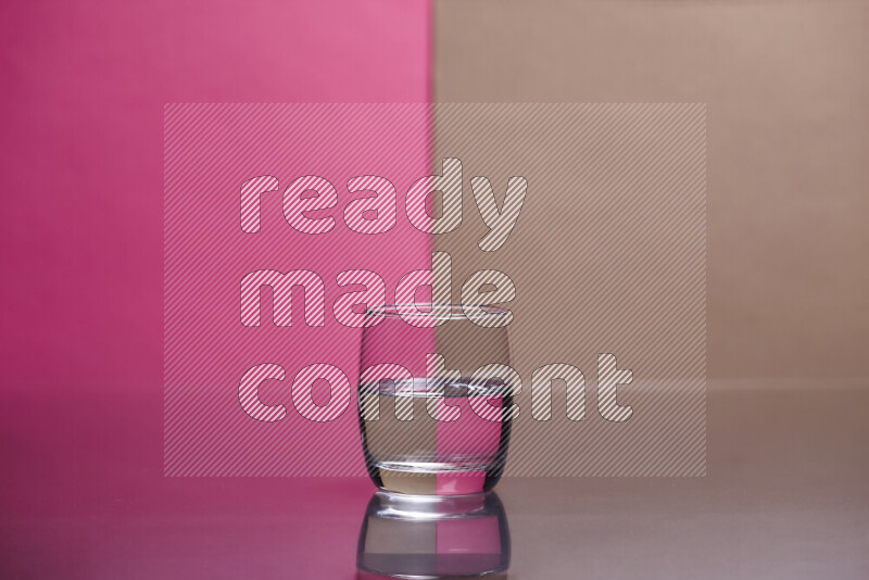 The image features a clear glassware filled with water, set against pink and beige background