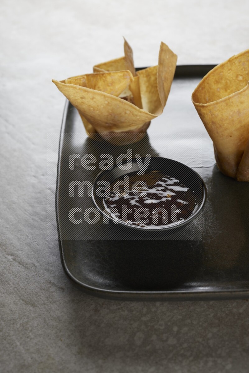 wonton cups with soy sauce ramkin on rectangle dark grey ceramic plate on grey textured counter top