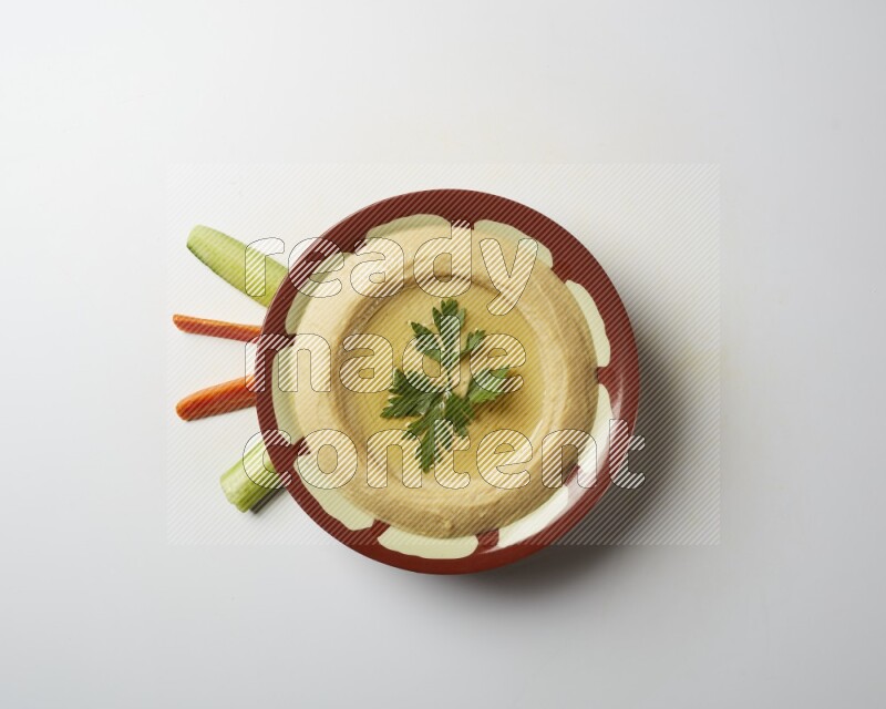 Hummus in a traditional plate garnished with parsley on a white background