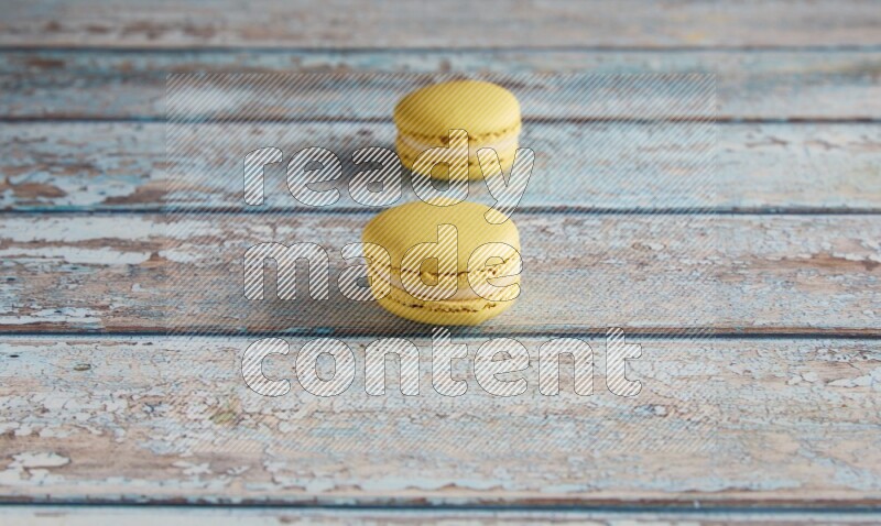 45º Shot of two Yellow Lime macarons on light blue wooden background