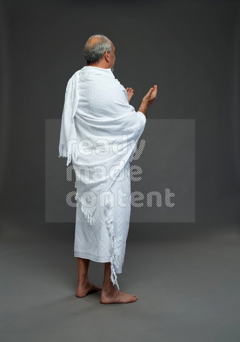 A man wearing Ehram Standing dua'a on gray background