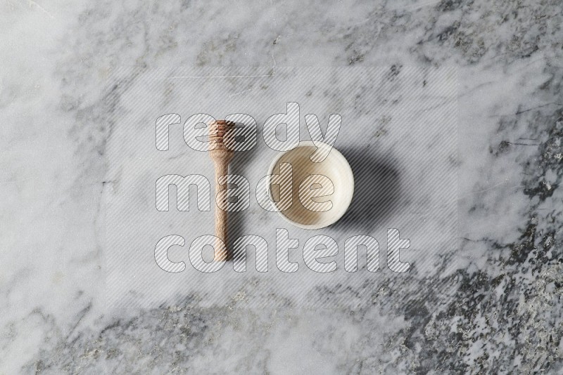 White Pottery Bowl with wooden honey handle on the side on grey marble flooring, Top view