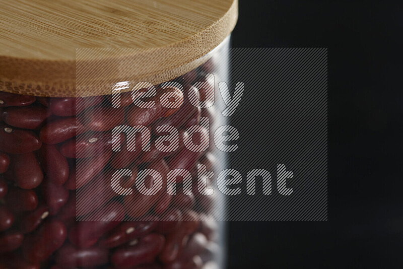 Red kidney beans in a glass jar on black background