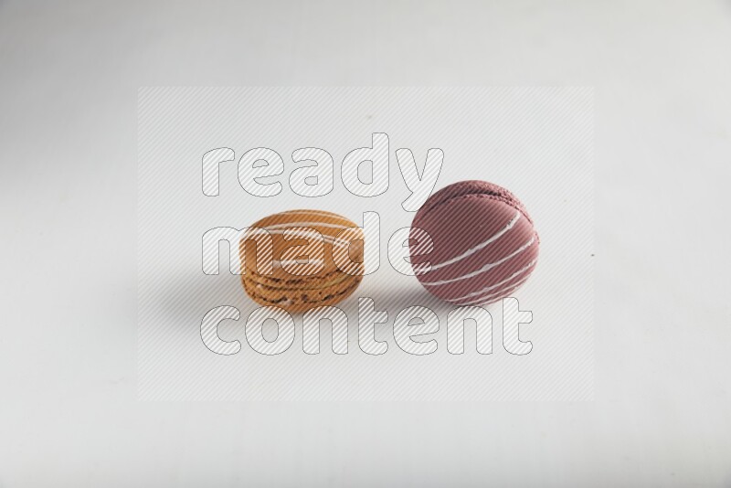 45º Shot of of two assorted Brown Irish Cream, and Red Poppy Flower macarons on white background