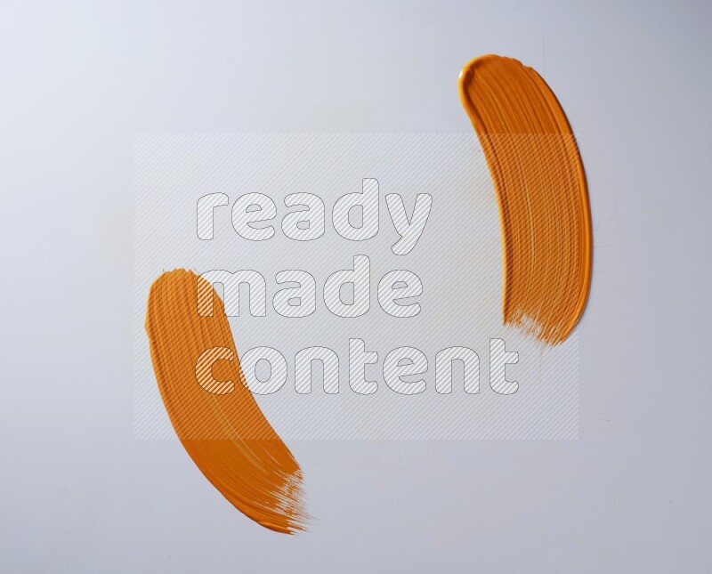 An orange curved painting brush stroke on a white background