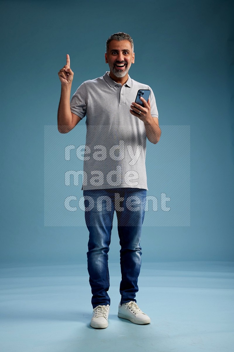 Man Standing texting on phone on blue background