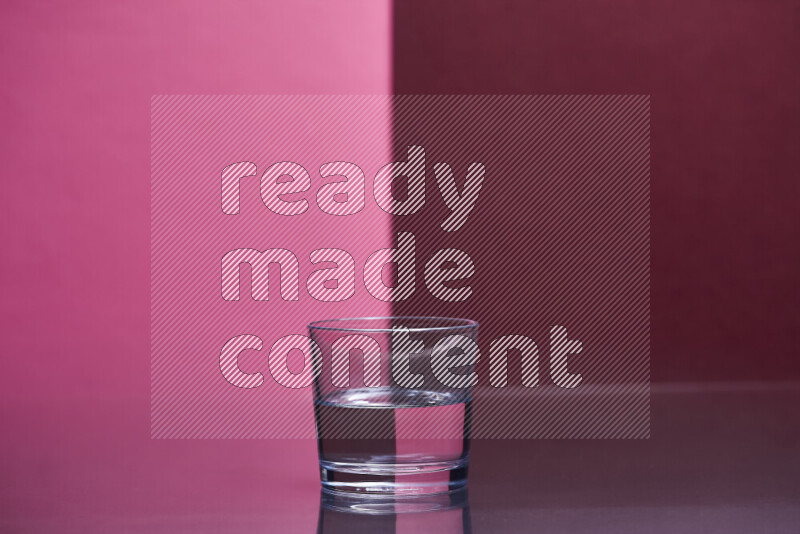 The image features a clear glassware filled with water, set against pink and dark red background