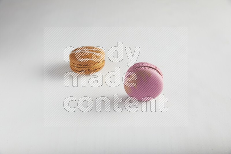 45º Shot of of two assorted Brown Irish Cream, and Purple Strawberry macarons on white background