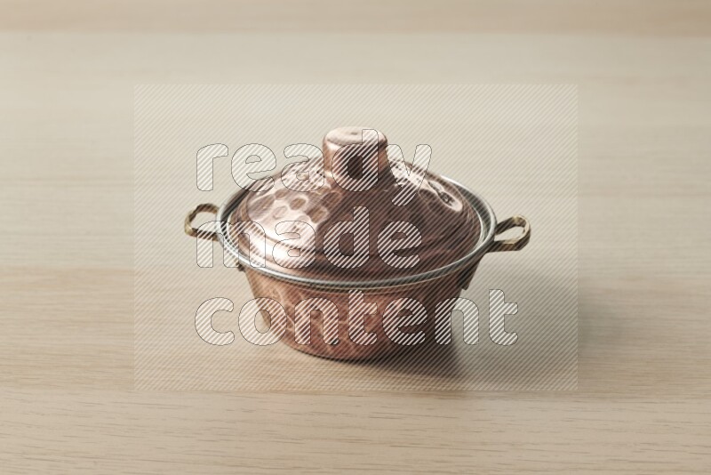 A small copper pot on light wooden background