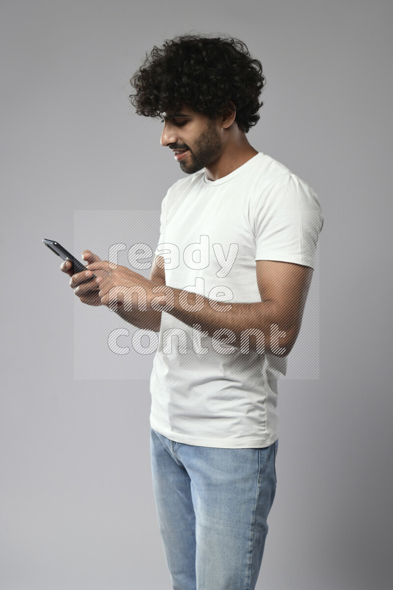 A man wearing casual standing and browsing on the phone on white background