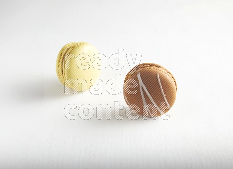 45º Shot of of two assorted Brown Irish Cream, and Yellow Lime macarons on white background