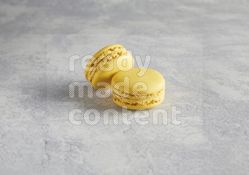 45º Shot of two Yellow Lemon macarons  on white  marble background