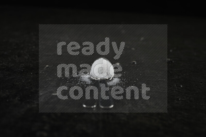 ملعقتان معدنيتان ممتلئتان بالملح الأبيض على خلفية سوداء