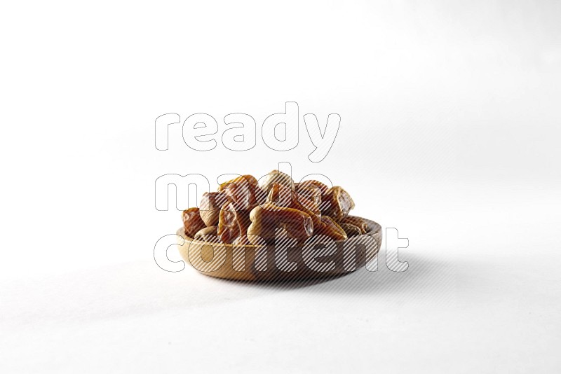 Dates in a wooden bowl on white background