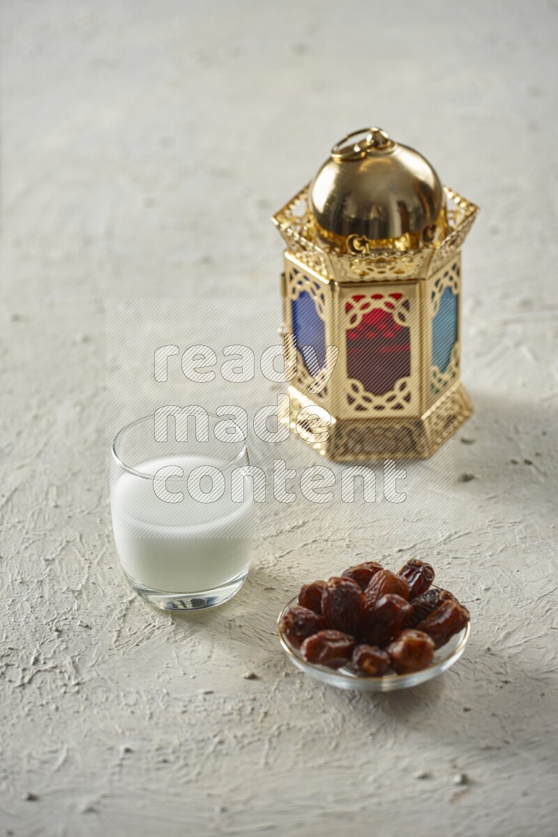A golden lantern with different drinks, dates, nuts, prayer beads and quran on textured white background