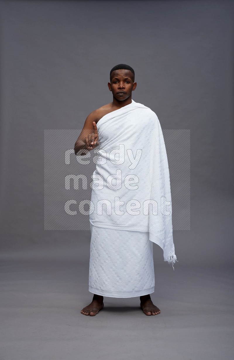 A man wearing Ehram Standing Interacting with the camera on gray background