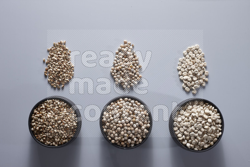 Legumes in pottery bowls on light grey background