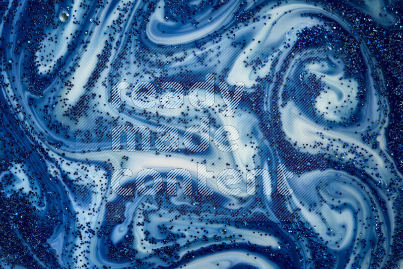 A close-up of sparkling blue glitter scattered on swirling blue and white background