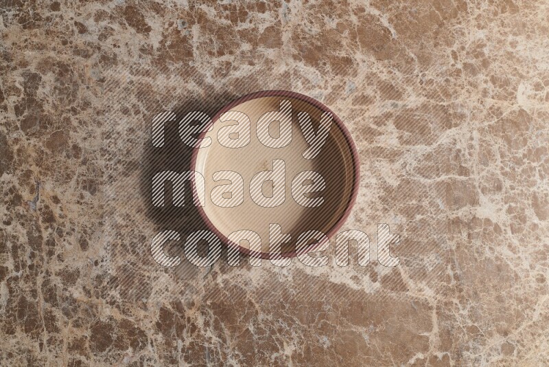 A beige pottery oven plate on beige marble background