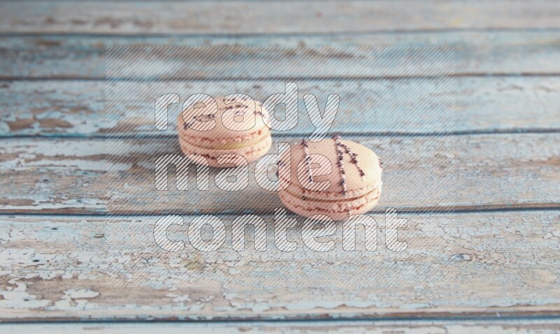 45º Shot of two pink orange blossom macarons on light blue wooden background