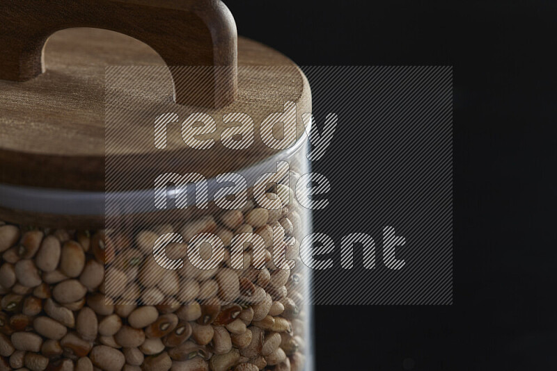 Black-eyed peas in a glass jar on black background