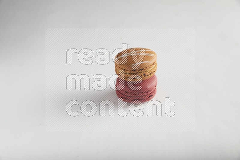 45º Shot of of two assorted Brown Irish Cream, and Red Velvet macarons on white background