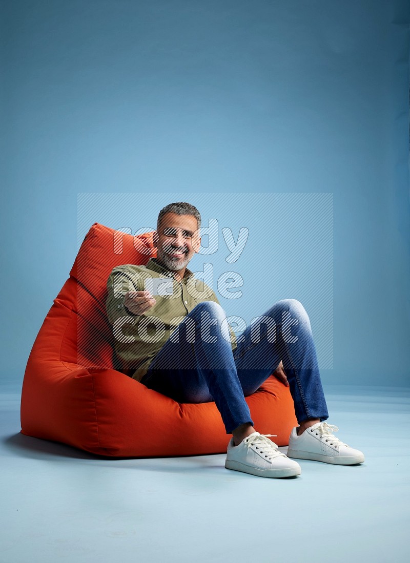 A man sitting on an orange beanbag and holding ATM card