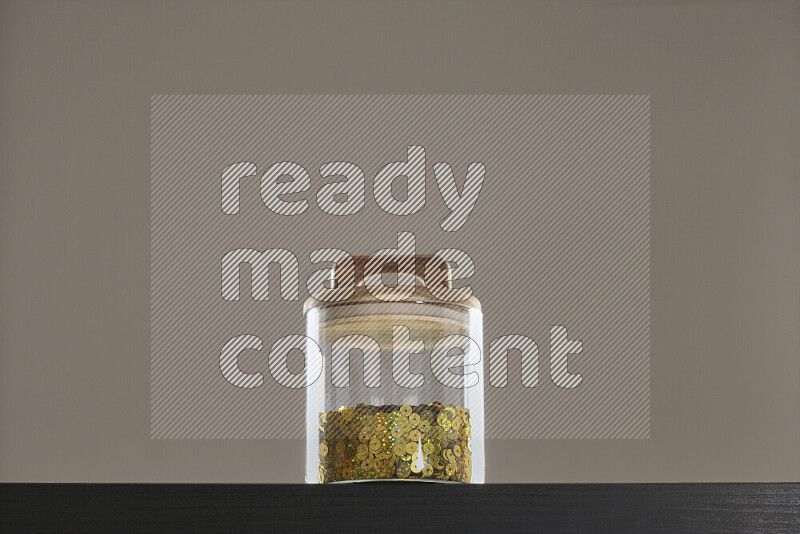 Sequins in a glass jar on black background