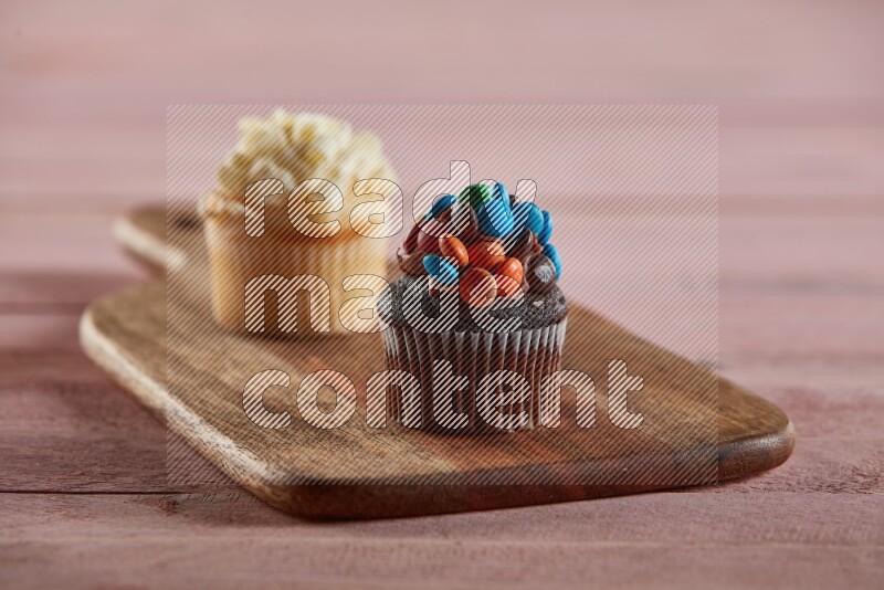 Chocolate mini cupcake topped with m&ms on a wooden board