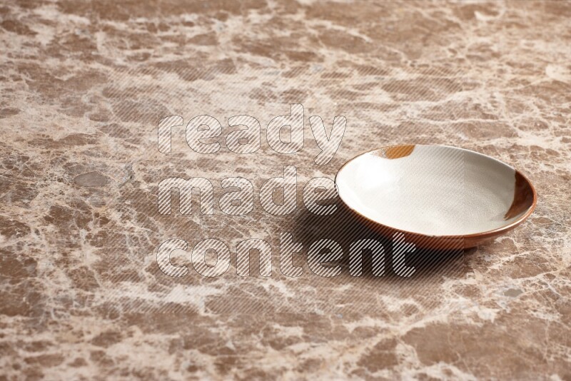 A multicolored pottery plate on beige marble background