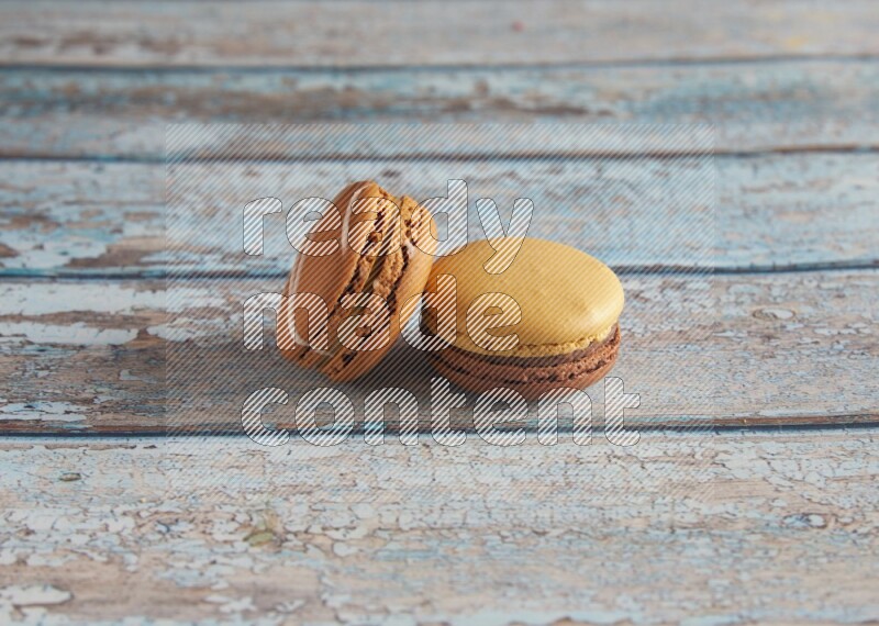 45º Shot of of two assorted Brown Irish Cream, and Yellow, and Brown Chai Latte macarons  on light blue background