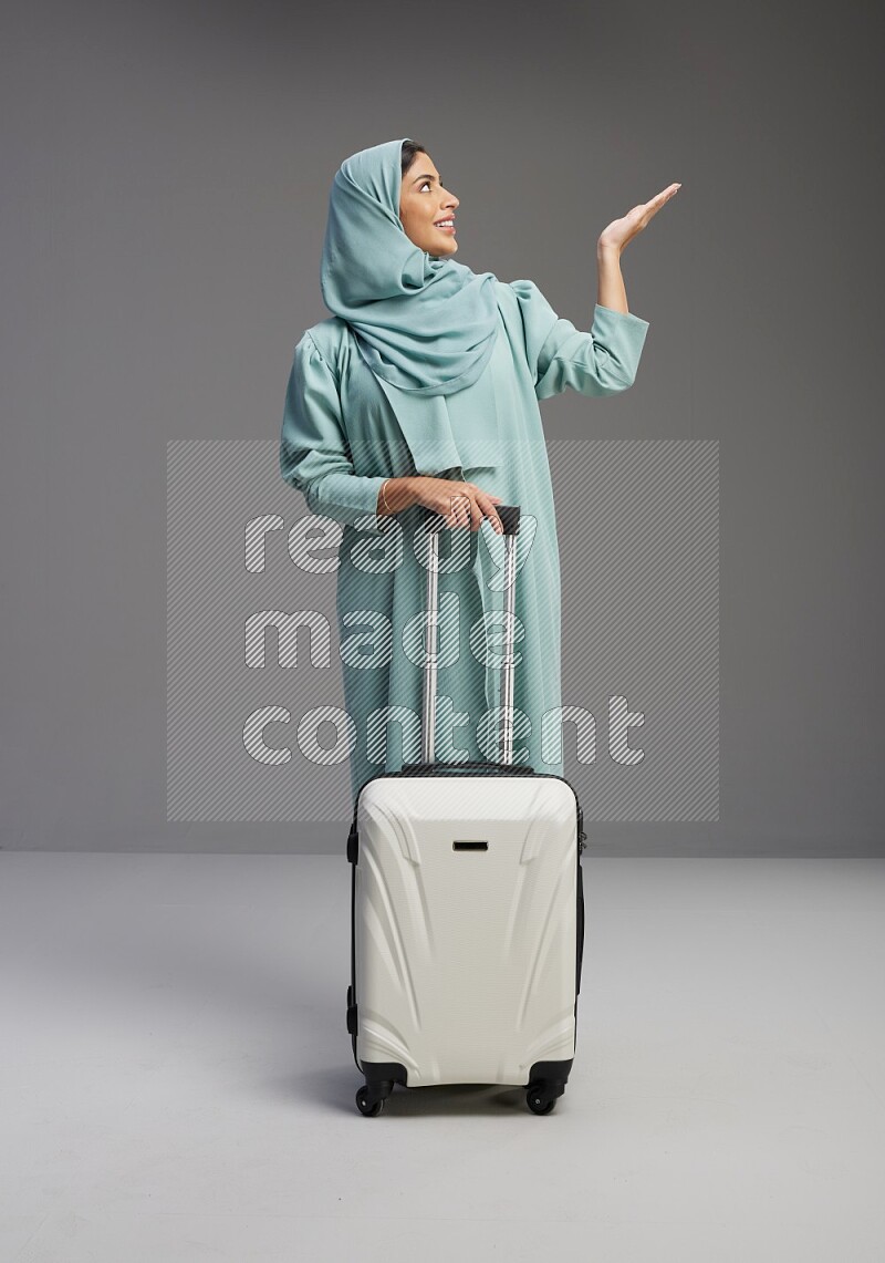 Saudi Woman wearing Abaya standing holding Travel bag on Gray background